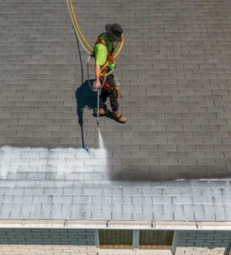 An employee spraying chemicals on a residential roof