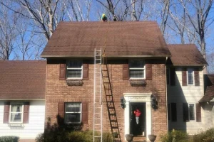 A technician applying roof rejuvenation spray to asphalt shingles
